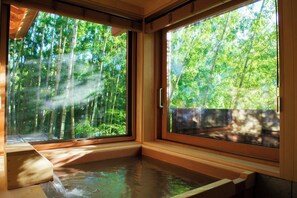 A room with a large window overlooking a bamboo forest.