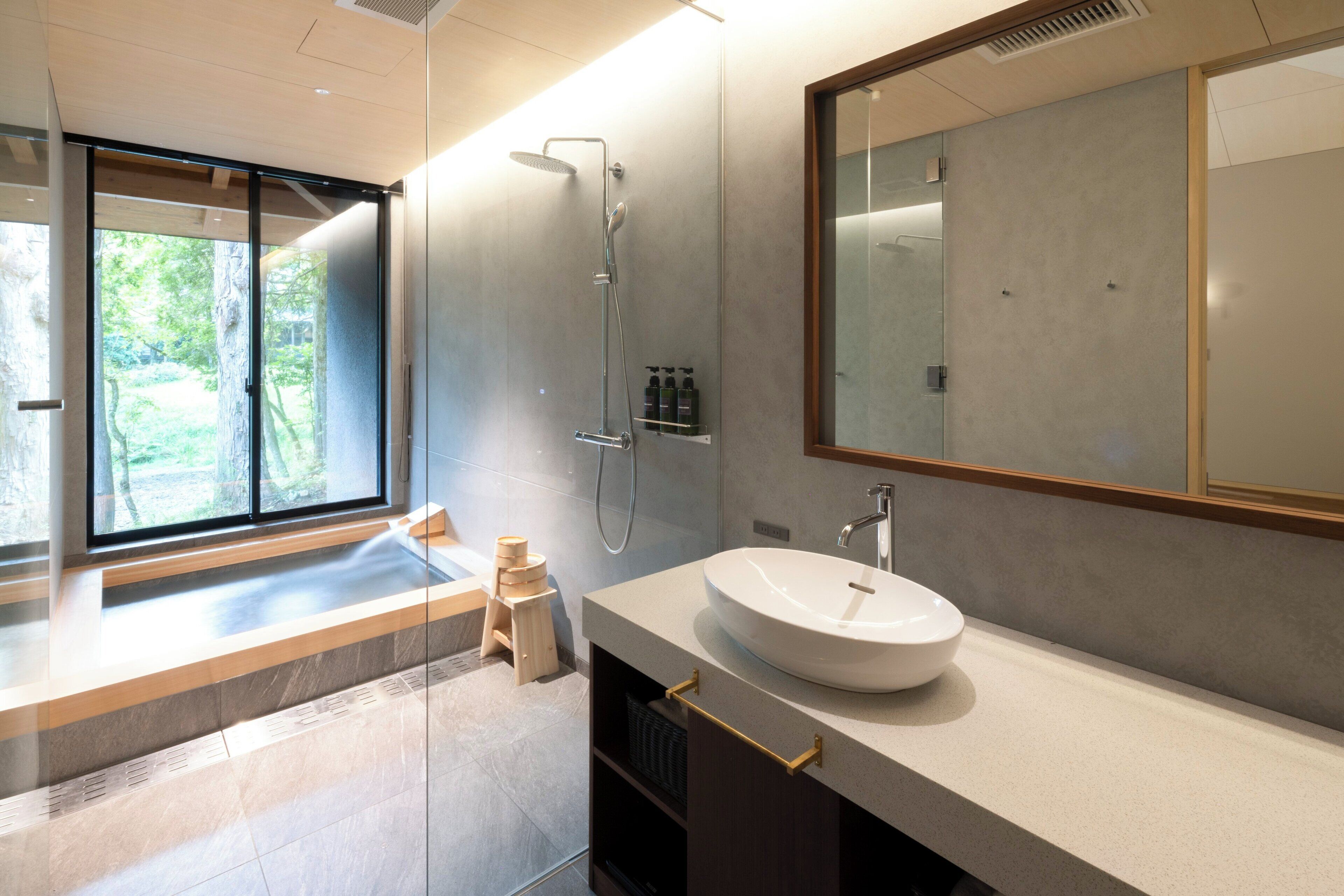 A modern bathroom with a large window, a built-in sink, and a shower.