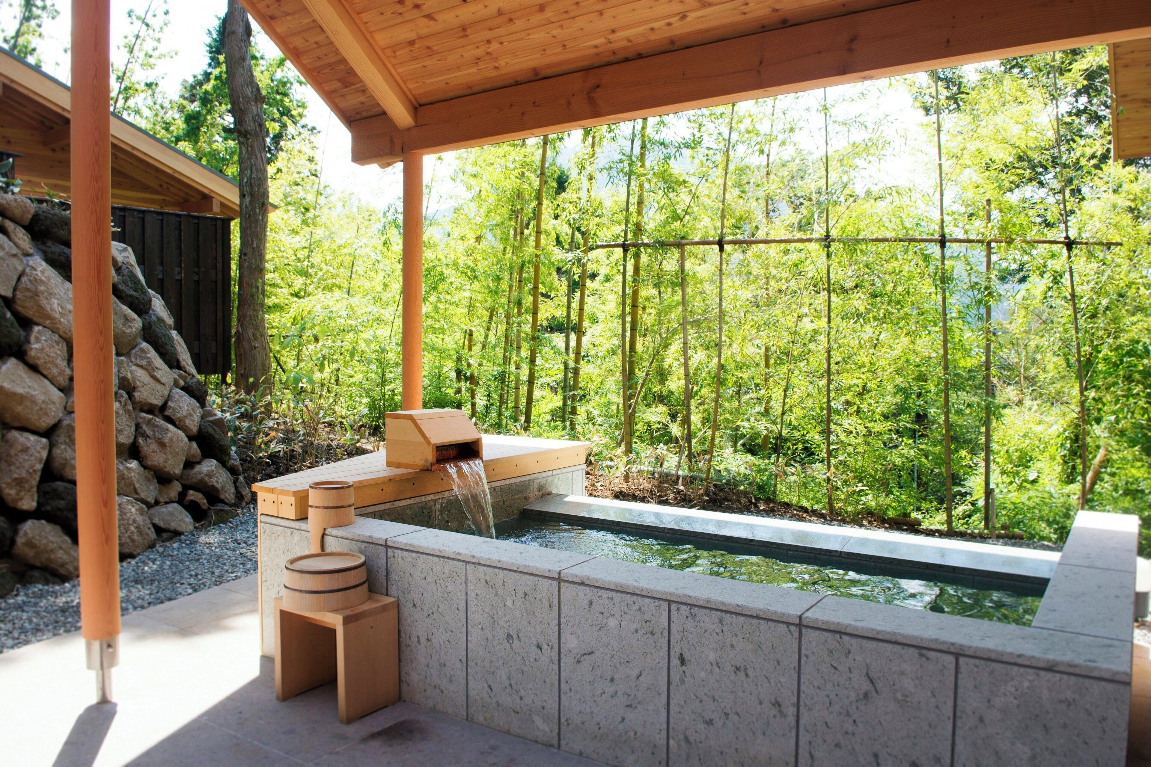 Uma área de spa com hidromassagem, assentos de madeira e uma parede de pedra.