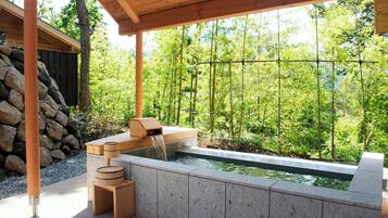 Uma área de spa com hidromassagem, assentos de madeira e uma parede de pedra.