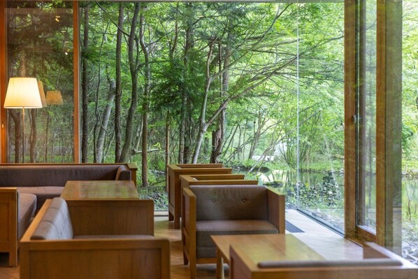 Un restaurante con mobiliario de madera y ventanas amplias que ofrecen vistas a un bosque.