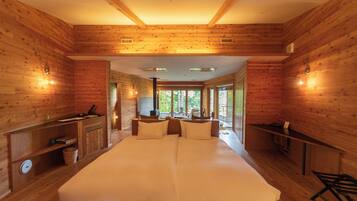 Une cabane en bois avec un grand lit, des étagères intégrées et une vue sur l’extérieur.