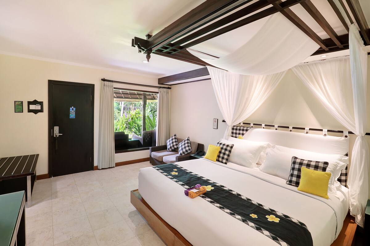 A hotel room with a large bed, a desk, and a window with curtains.
