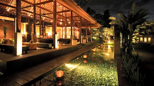Un área de descanso al aire libre con buena iluminación, piscina, terraza de madera y disposición de asientos.