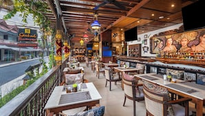 A restaurant with outdoor seating, wooden tables, and a bar area. - Rama Residence Padma (Legian)