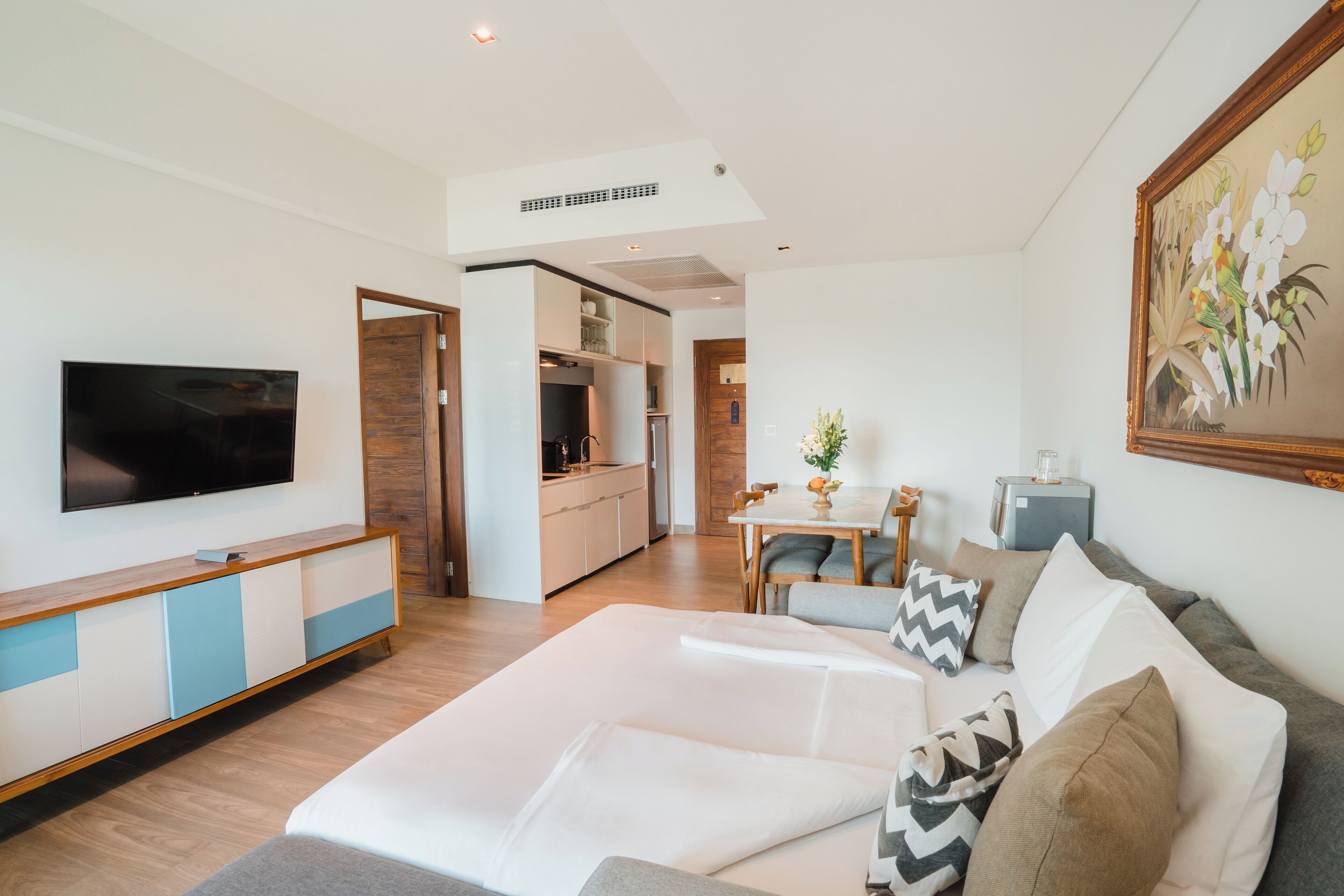 A modern living room with a sofa, a TV, and a dining area with a table and chairs.