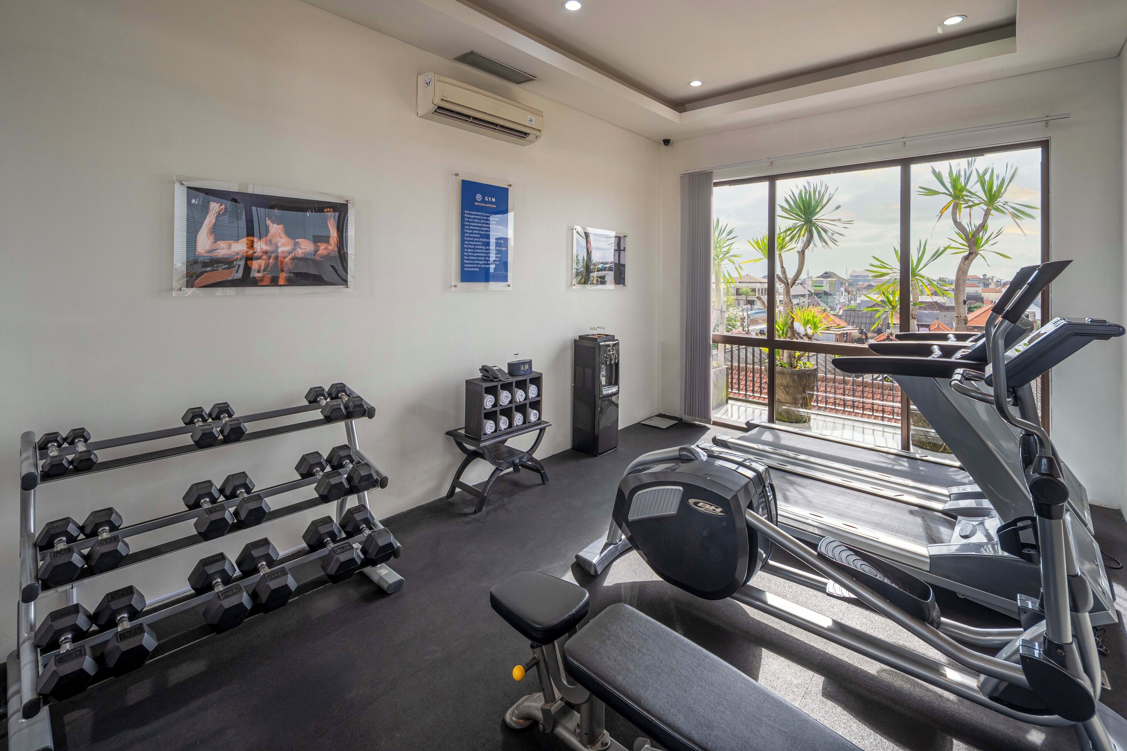 A gym with dumbbells, a bench, and a treadmill.