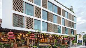 Un edificio moderno con amplios ventanales y un espacio exterior cubierto con plantas e iluminación colgante.