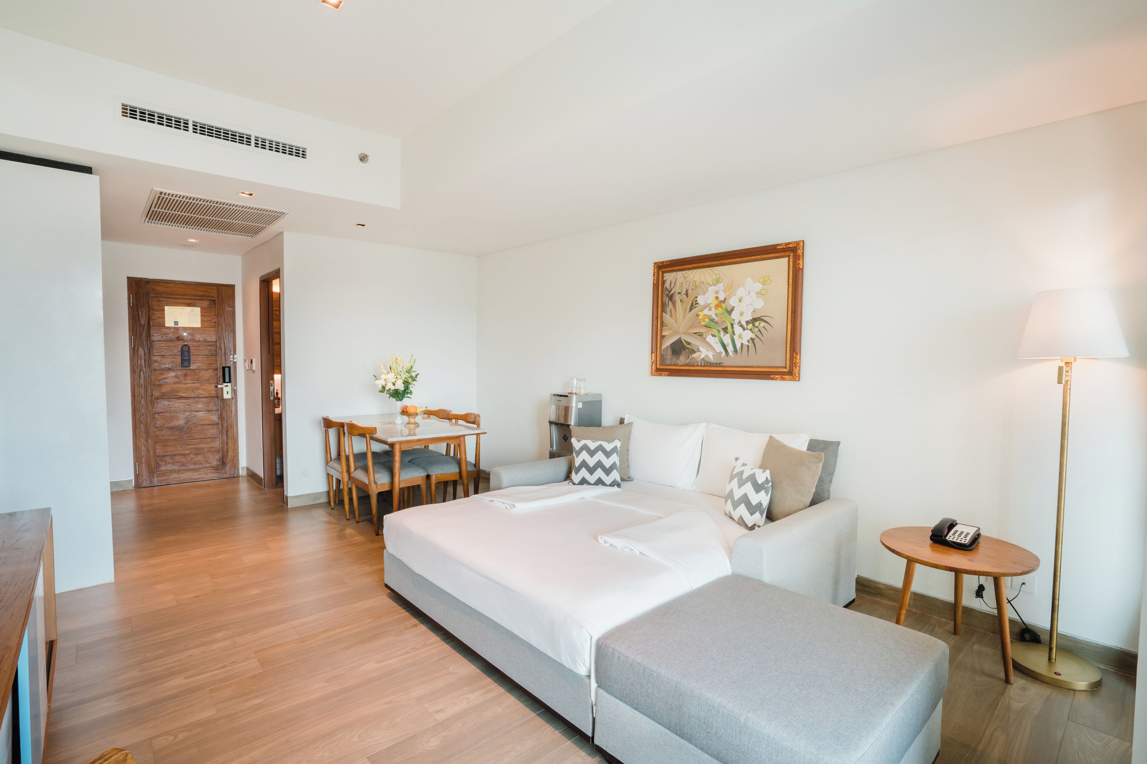 Una habitación de hotel moderna con una cama grande, un escritorio con silla, una mesita y una lámpara.