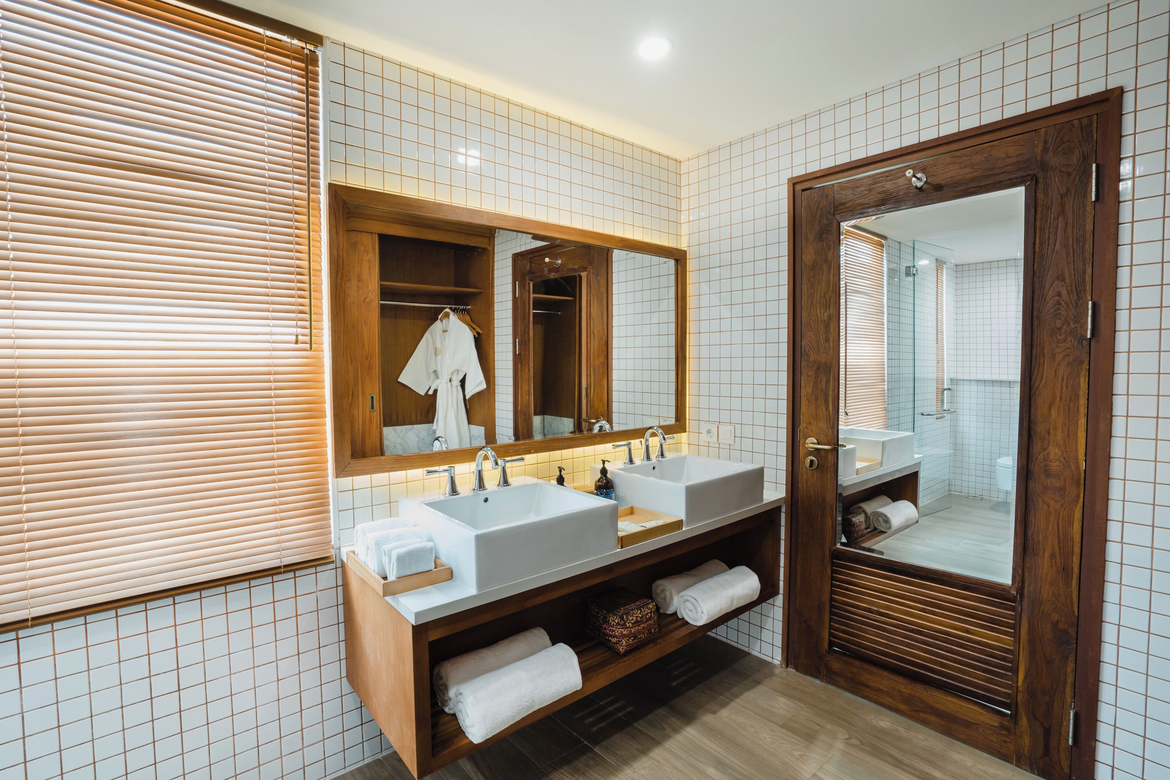 Un baño moderno con dos lavamanos, un espejo grande y un mueble de tocador de madera.