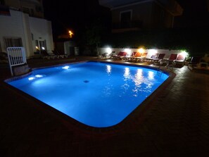 A swimming pool with a tiled edge, surrounded by lounge chairs and a brick walkway. - Avlu 4 Apart Hotel (Marmaris)