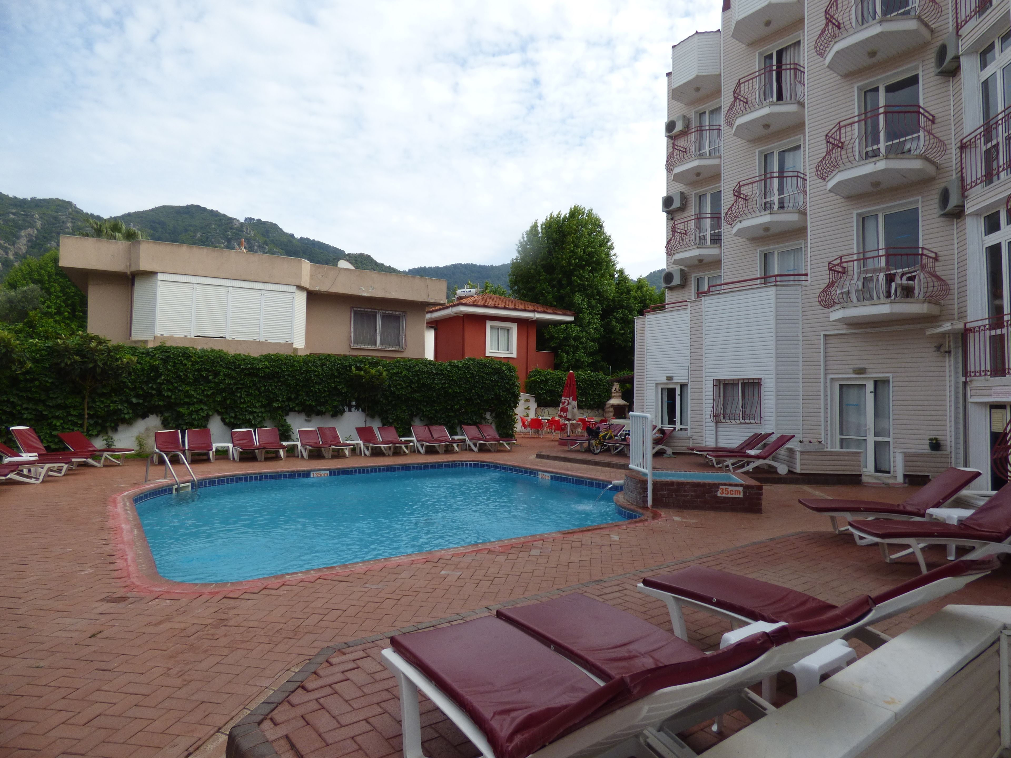 A swimming pool with sun loungers and a red-tiled deck.