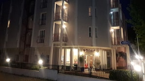 A multi-story building with balconies, a sign for 'AVLU 4 Apartments', and a street sign indicating '312 SOKAR'.
