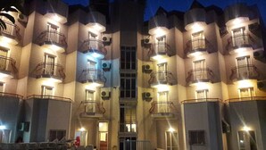 A multi-story hotel with balconies, a swimming pool, and a central entrance.