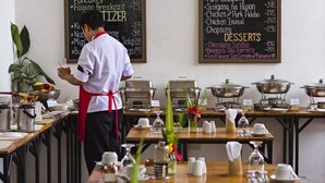 A buffet setup with a chef preparing food, a menu board, and various food service stations. - Vela Terraces Hotel (Coron)
