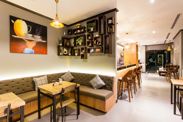 Un interior moderno con un sofá modular, mesas de madera y una zona de bar.
