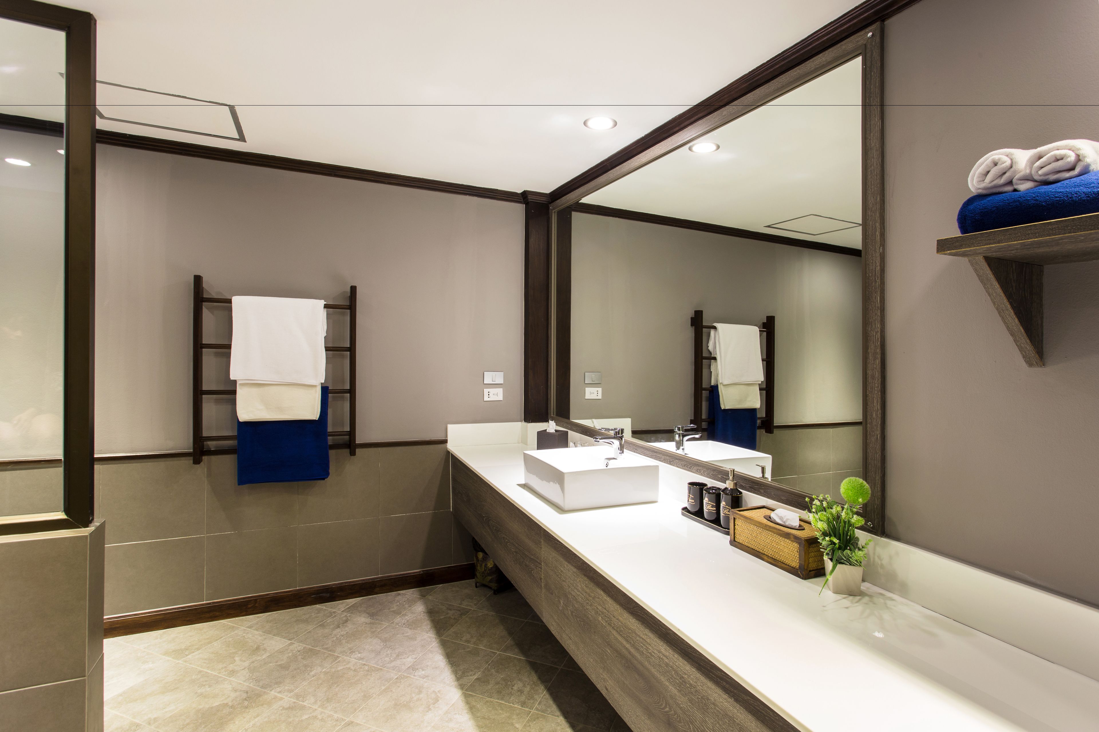A modern bathroom with a large mirror, a wooden vanity, and a towel rack.