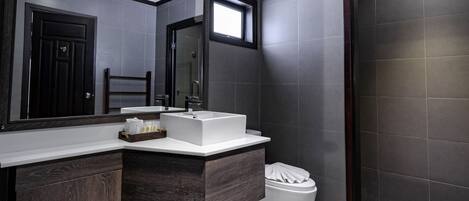 A modern bathroom with a dark wood vanity, a white sink, and a large mirror.