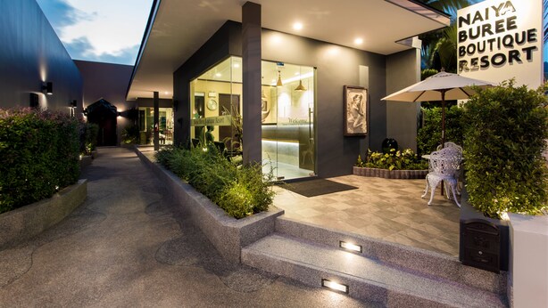 Het uiterlijk van Naiya Buree Boutique Resort met een modern design, met een glazen entree, buiten zitplaatsen en een goed verlicht pad naar de ingang.