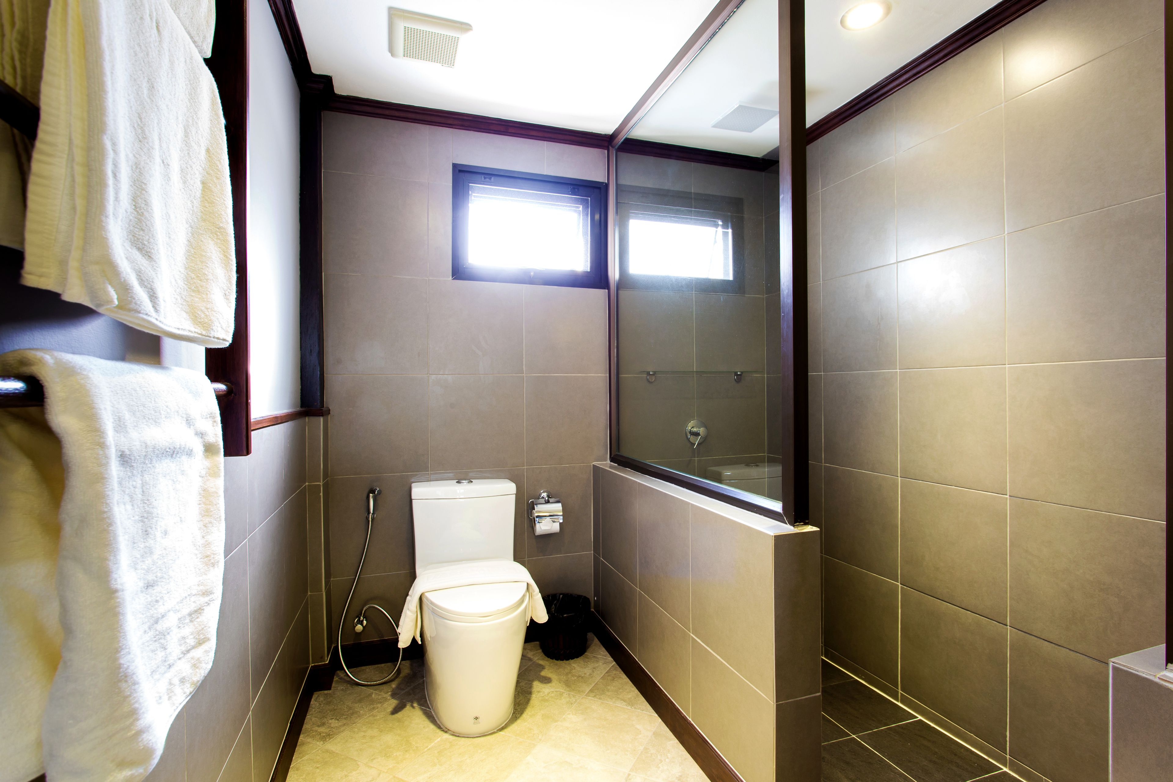 Ein kleines, modernes Badezimmer mit Toilette, Duschkabine und einem Fenster für Tageslicht.