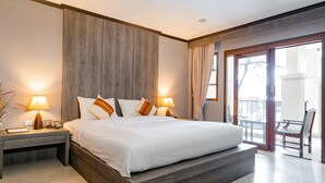 Een groot bed met een houten hoofdbord, twee bedlampen, een nachtkastje en uitzicht op het balkon.