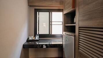 A compact kitchen with a built-in refrigerator, a window with blinds, and a countertop with a few items.