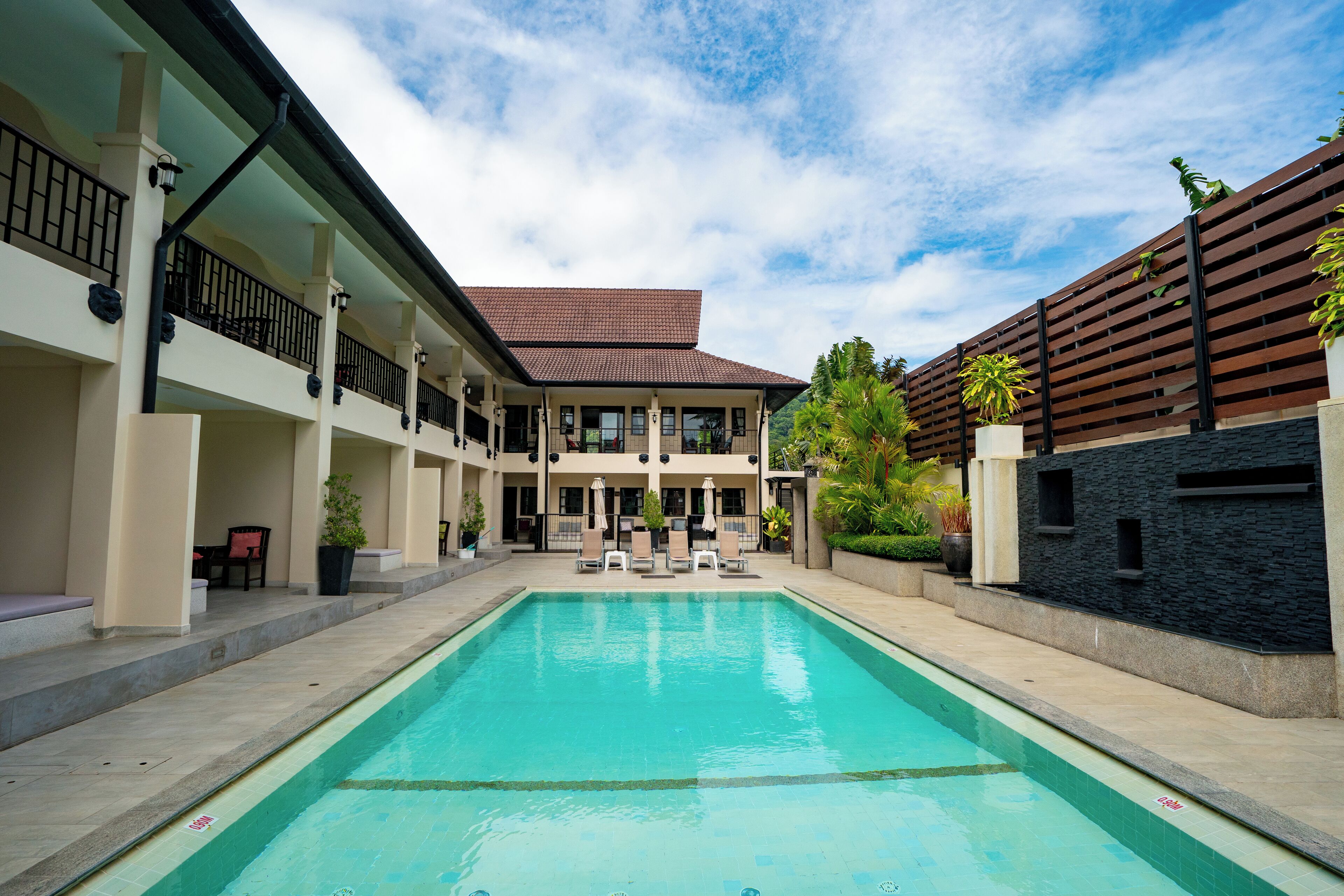 A swimming pool with lounge chairs and a covered seating area.