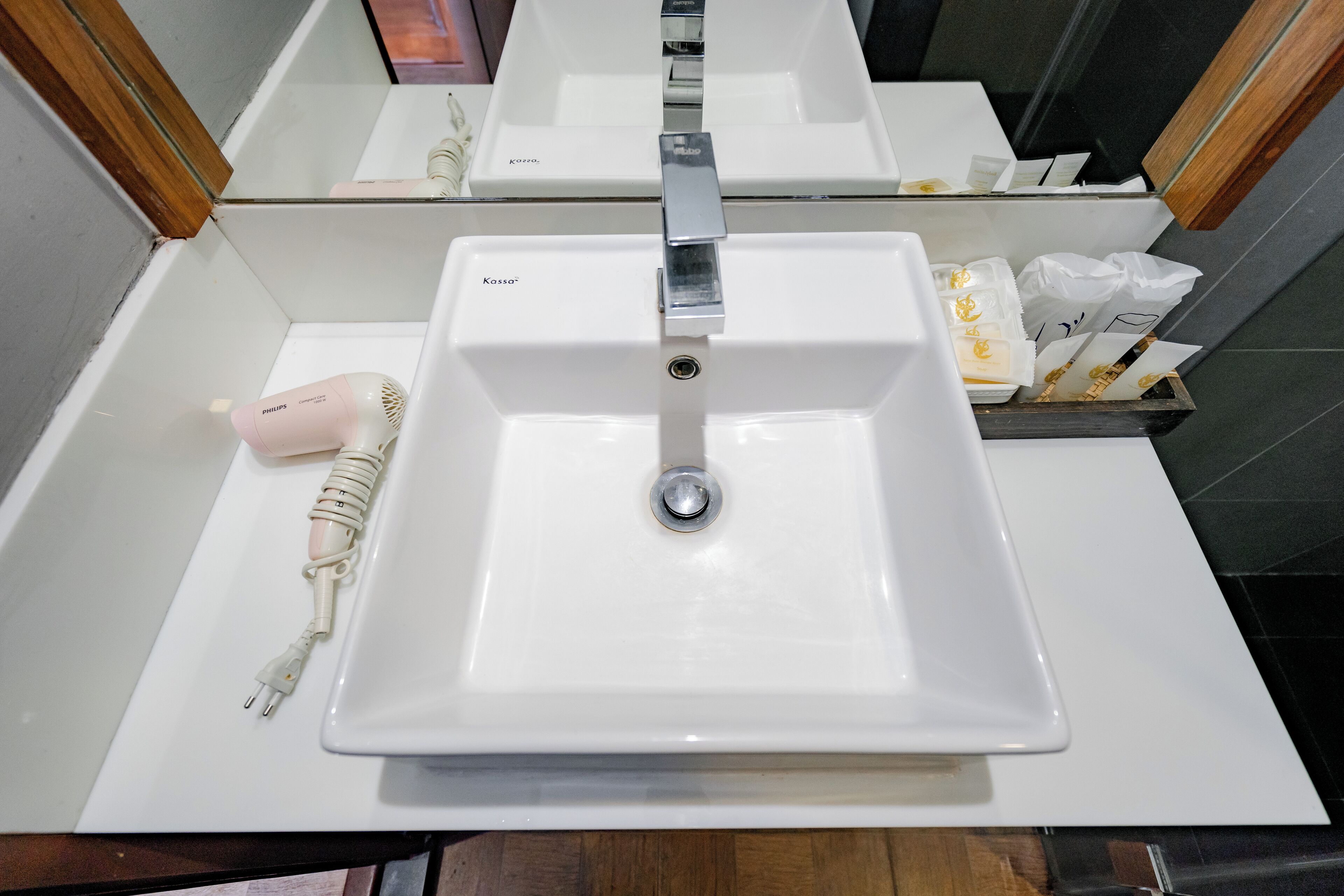 A bathroom with a white sink, a mirror, and toiletries.
