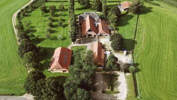 Vista aérea de una propiedad con varias edificaciones, rodeada de campos verdes y árboles.