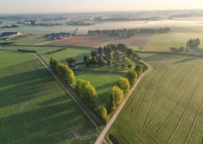 An aerial view of a rural landscape with fields, a road, and a cluster of buildings surrounded by trees. - Havezathe Carpe Diem (Vethuizen)