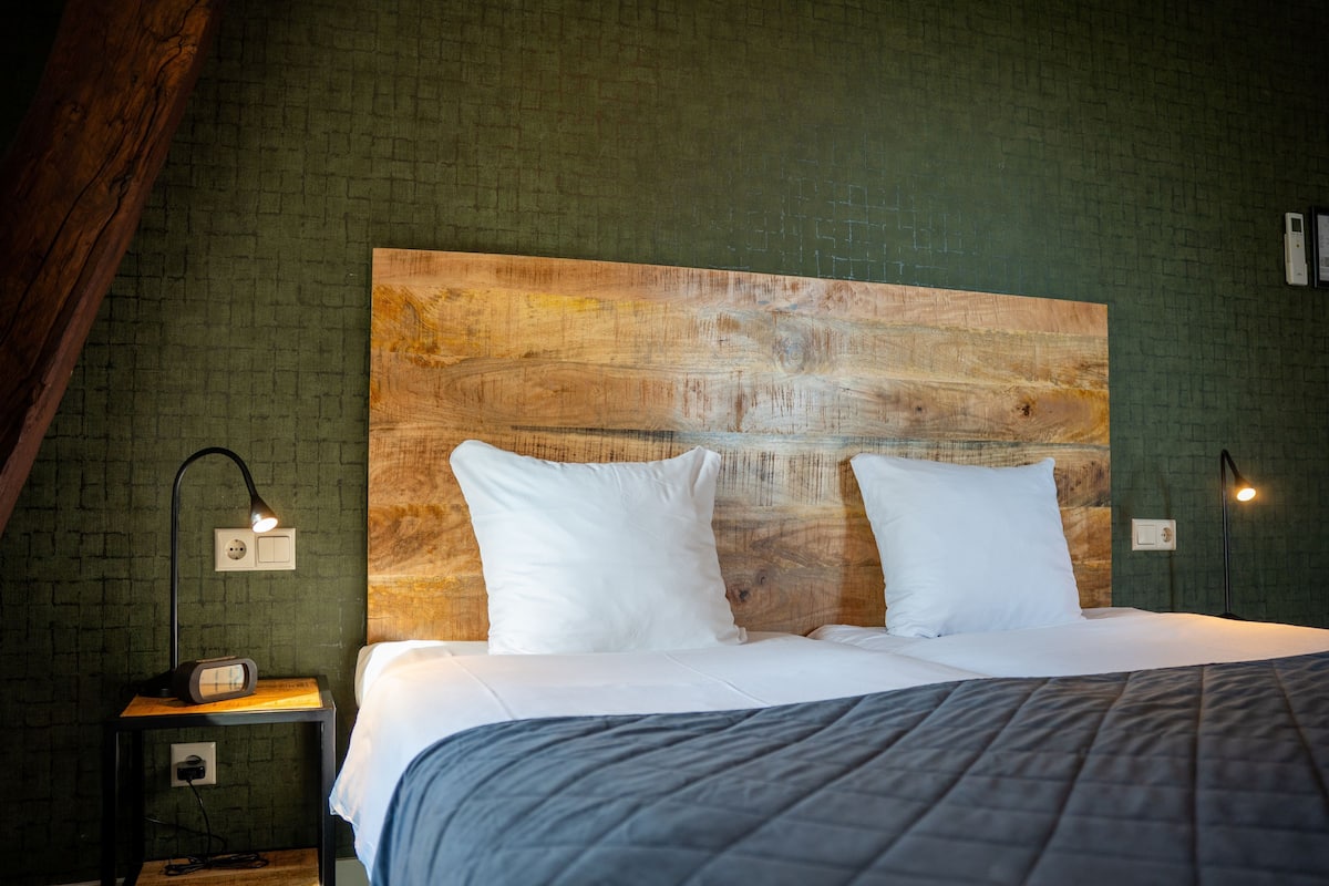 A bed with white bedding, a wooden headboard, and two bedside lamps.