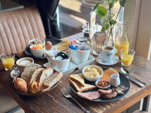 A breakfast table with croissants, toast, eggs, beans, sausages, and juice. - Havezathe Carpe Diem (Vethuizen)