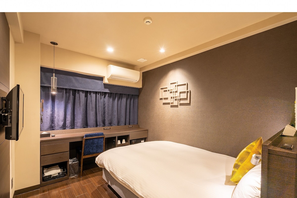Une chambre d’hôtel équipée d’un lit, d’un bureau, d’une chaise, d’une télévision et d’un appareil de climatisation.