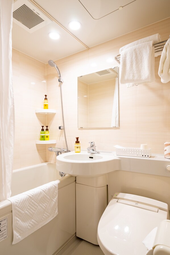 A bathroom with a bathtub, a sink, and a toilet. There are towels hanging on the wall and a showerhead above the sink. - Red Roof Inn Kamata (Tokyo)