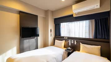 Une chambre d’hôtel avec deux lits, un téléviseur à écran plat, un climatiseur et une fenêtre avec des rideaux.
