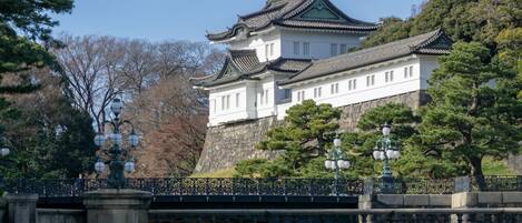 A traditional Japanese castle with a stone wall, wooden buildings, and a bridge.