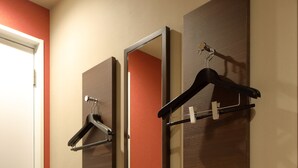 A hotel bathroom with three mirrors, a towel dispenser, and a coat hook.