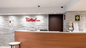 A reception area with a stone wall, a clock, and a sign for Red Roof Inn.