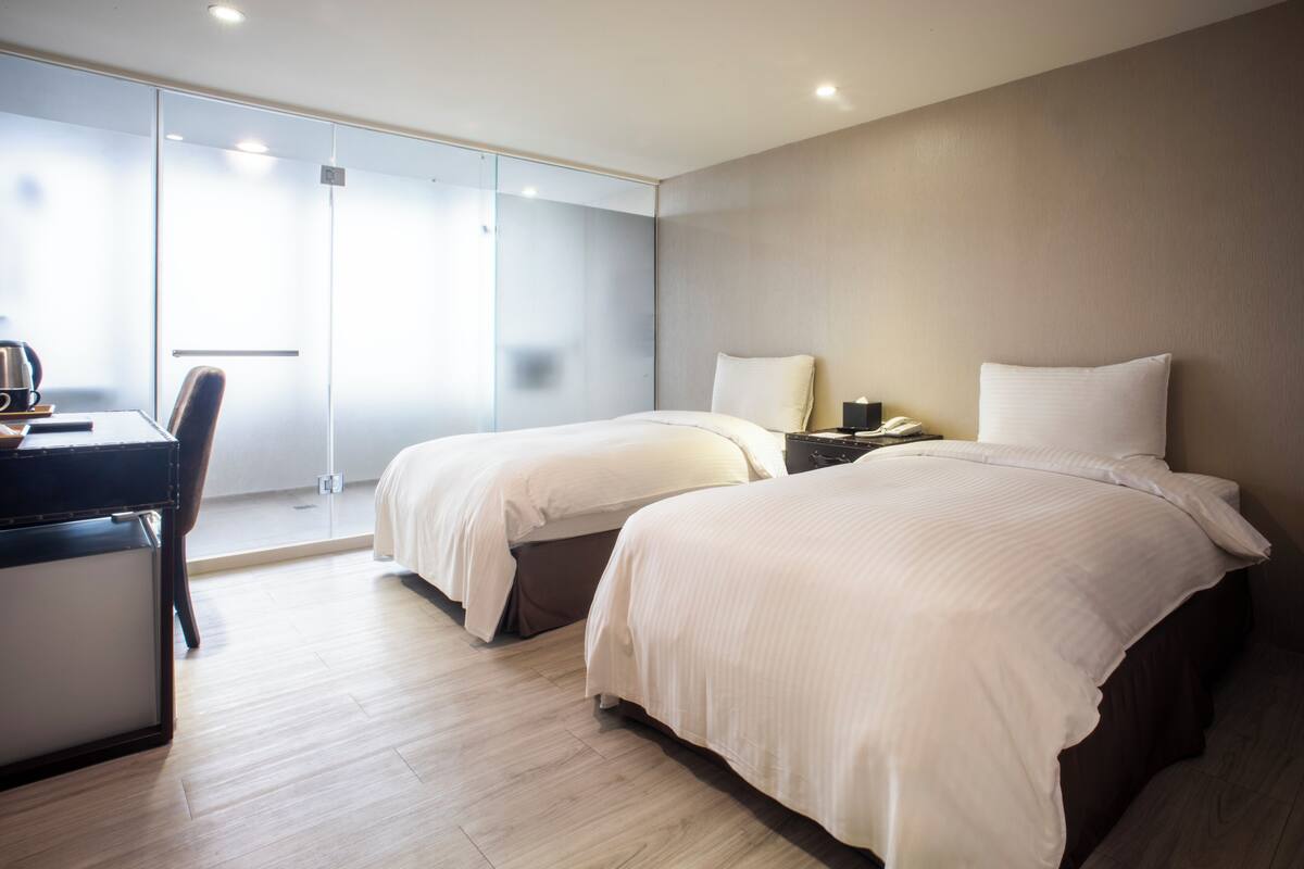 Une chambre d’hôtel avec deux lits, un bureau et une chaise.