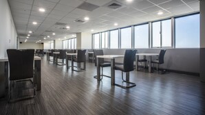 Een ruime cafetaria met hoge plafonds, veel natuurlijk licht en modern meubilair.