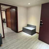 Una habitación con puerta de madera, un banco y suelo de baldosas.