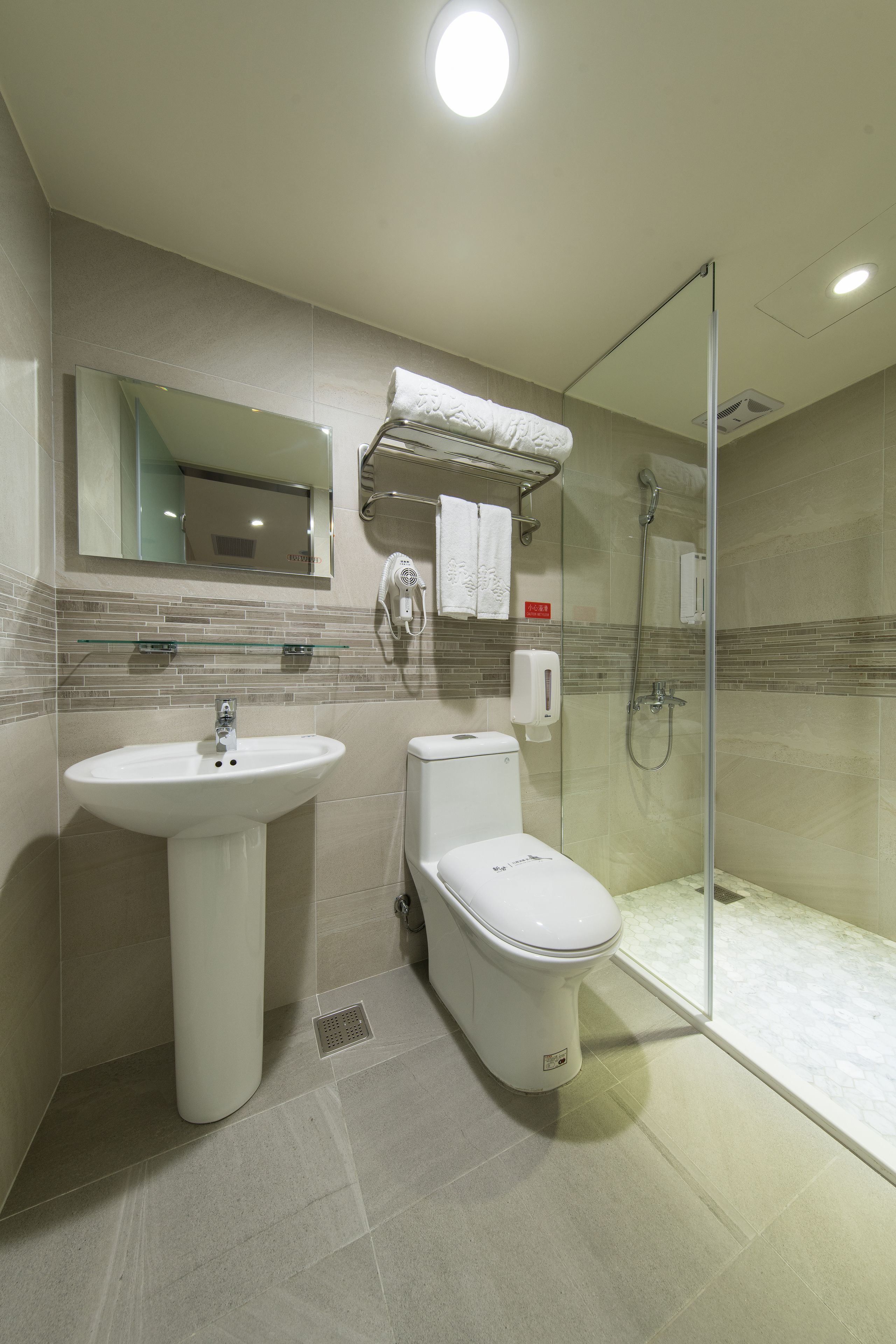 A modern bathroom with a glass-enclosed shower, a white sink, and a toilet.