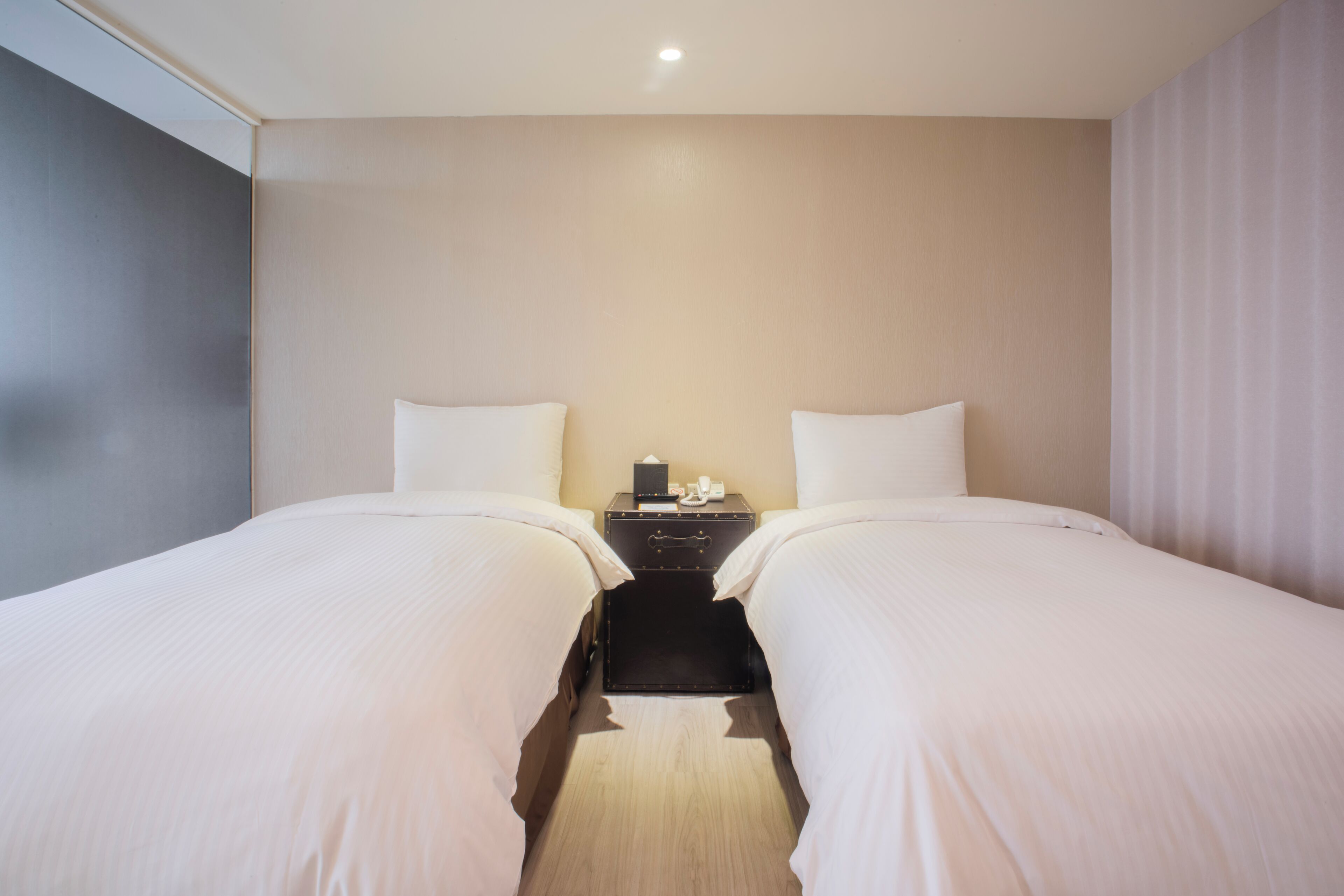 Una habitación de hotel con dos camas, una mesita de noche y una lámpara.