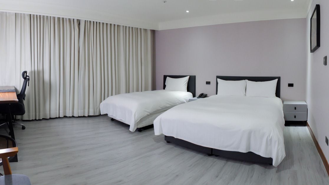 Ein Hotelzimmer mit zwei Betten, einem Schreibtisch und einem Stuhl.