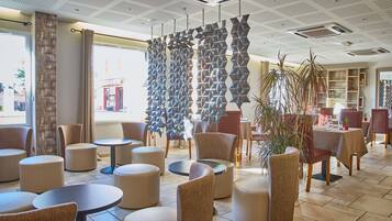 A modern interior with round tables and chairs, a geometric wall feature, and a view of the outside.