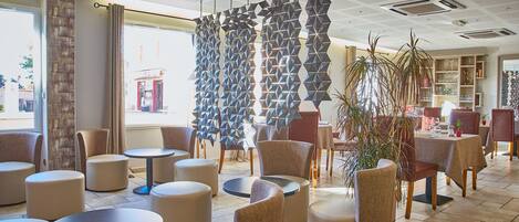 A modern interior with round tables and chairs, a geometric wall feature, and a view of the outside.
