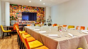 Une salle de conférence avec une longue table préparée pour une réunion, entourée de chaises orange.