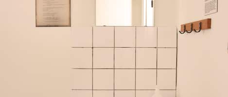 A bathroom with a white sink, a mirror above it, and a tiled wall.
