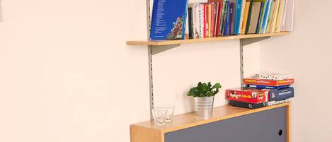 Una habitación con una estantería, una planta pequeña y un escritorio con una silla.