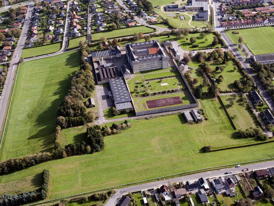 An aerial view of a large institutional building with multiple sports fields, surrounded by residential areas.